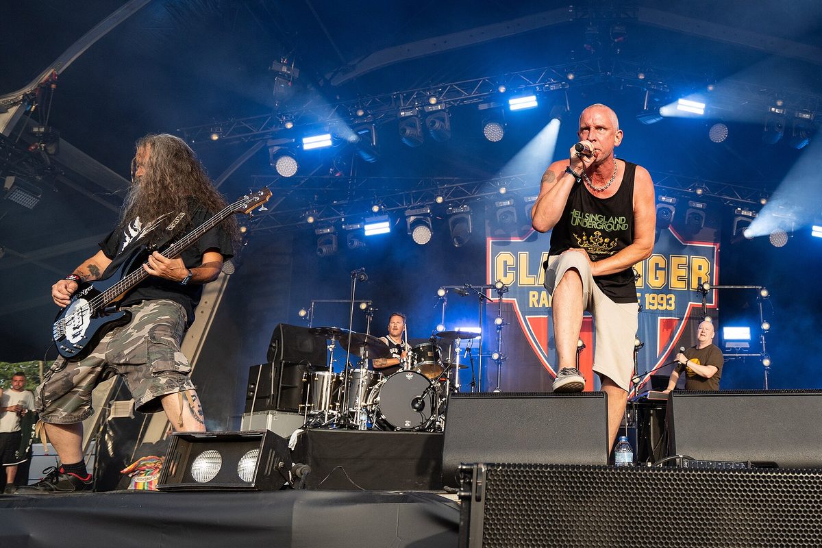 Clawfinger at Hellfest, Clisson, France, 28 June 2024: singer Zak Tell at the front, the bassist on the left and the drummer behind.